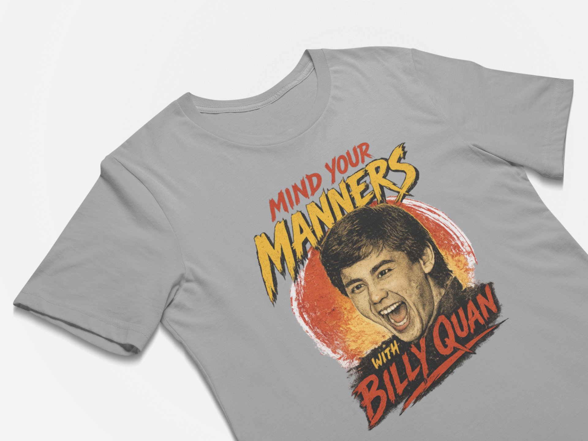 Gray t-shirt with a graphic of a man's face and text 'Mind your manners with Billy Quan' on a white background