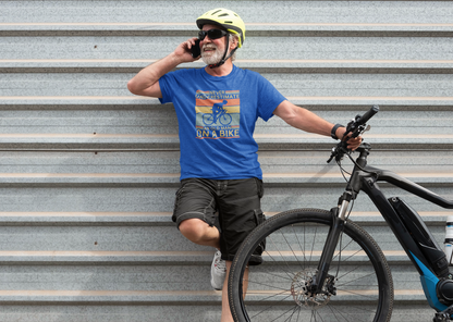 Man with a bicycle wearing a blue t-shirt and helmet, leaning against a metal wall.