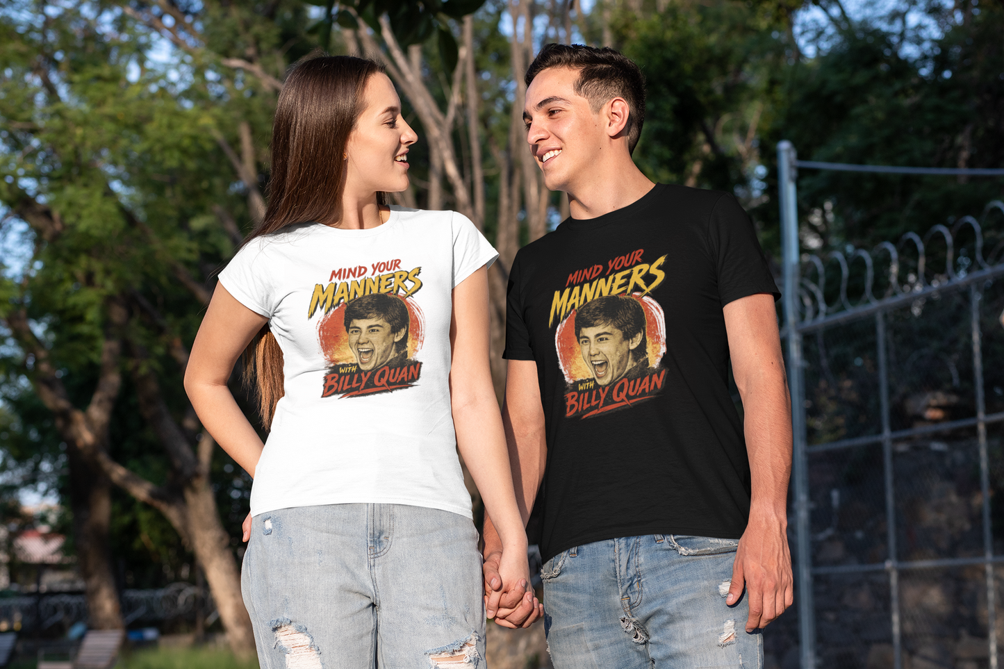 Two people wearing t-shirts with a graphic of a man and woman and text outdoors.