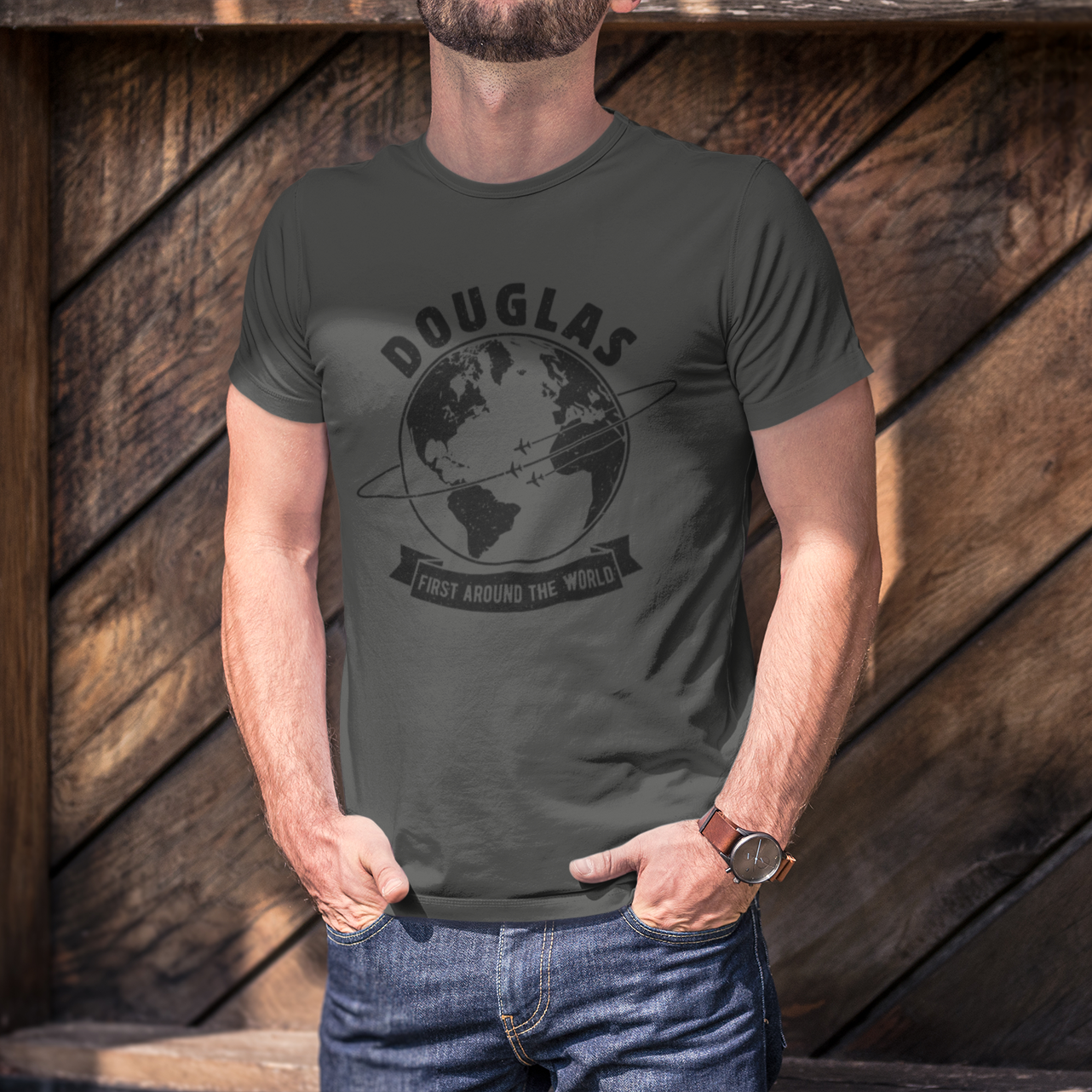 Man wearing a dark gray t-shirt with a Douglas Aircraft design and text, standing against a wooden wall.